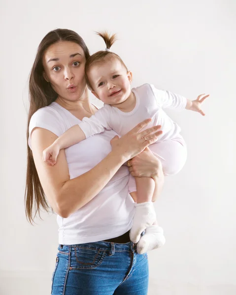 The young mother with long brown hair in jeans holding a baby