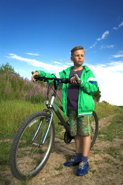 Young boy with a bicycle in nature rests.