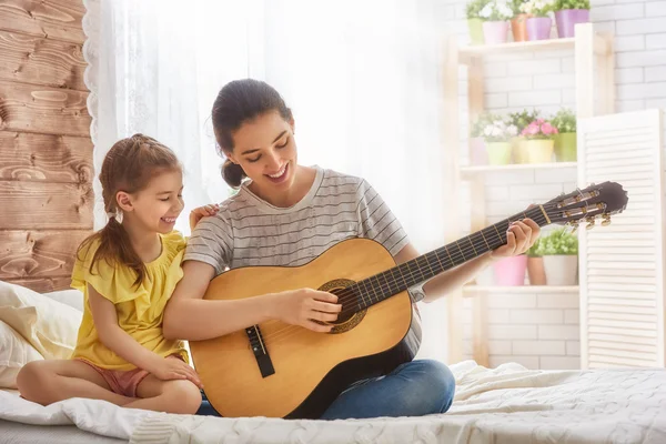 Mother and daughter playing guitar