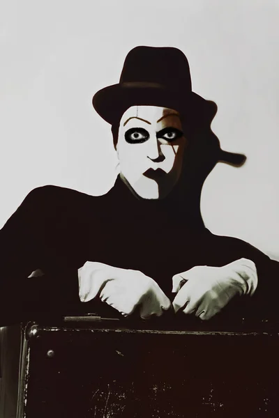 Theatrical actor with dark makeup on her face with a suitcase