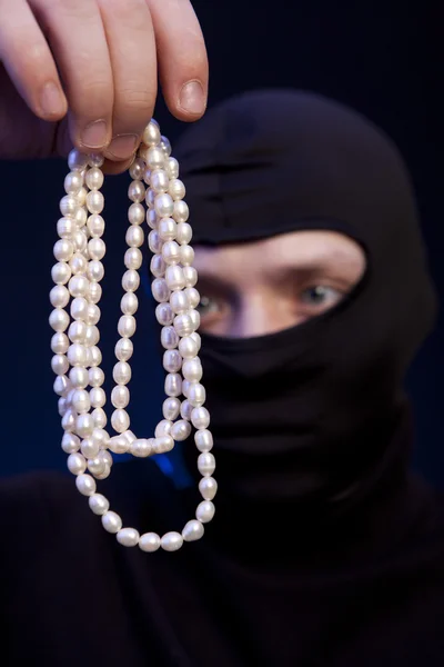 Thief. Man in black mask with a pearl necklace