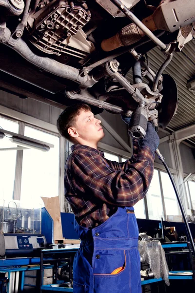 Car mechanic inspecting car wheel and suspension detail of lifte