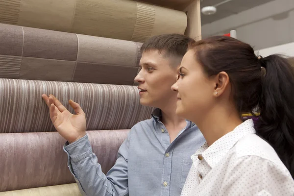 Happy family couple buying new wallpaper in store