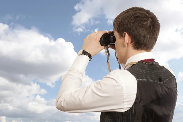 Businessman looks through a binoculars