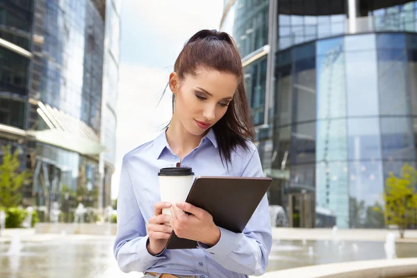 Woman drinking coffee and reading tablet