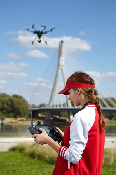 Woman with remote control and flying surveillance drone