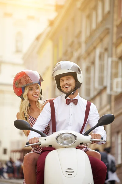 Couple riding scooter togethe