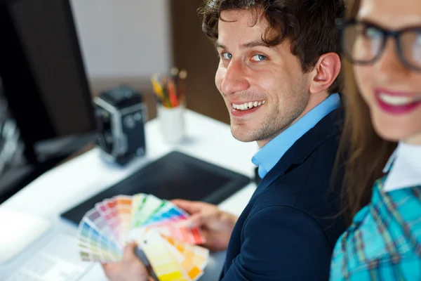 Young colleague looking to a color paint palette at home office