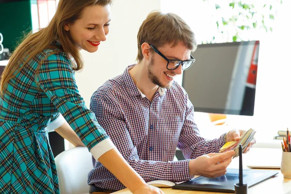 Man and woman looking to a color paint palette at home office