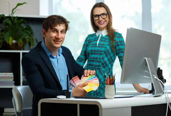 Young colleague looking to a color paint palette at home office