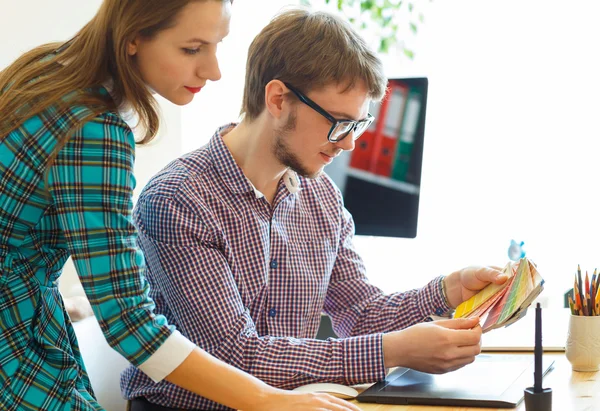 Young colleague looking to a color paint palette at home office