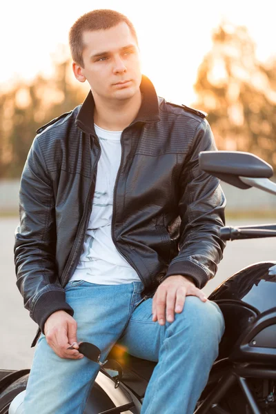 Biker man wearing a leather jacket sitting on his motorcycle out
