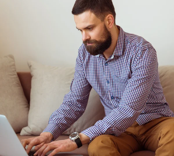 Young bearded man working on laptop