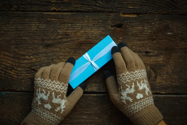 Hands in winter gloves with christmas gift box