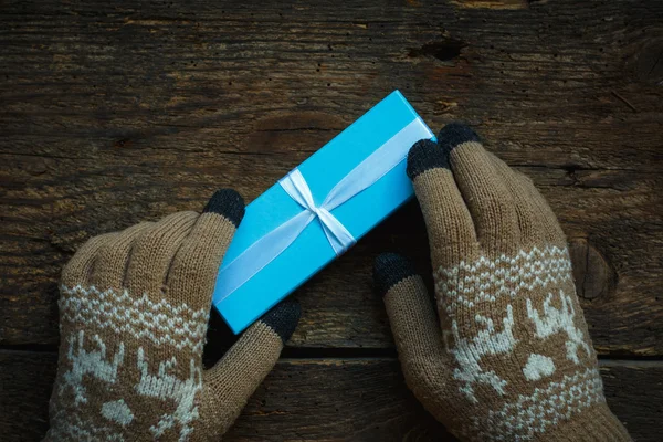 Hands in winter gloves with christmas gift box