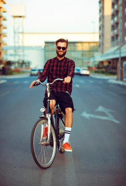 Young man in sunglasses riding a bike on city street
