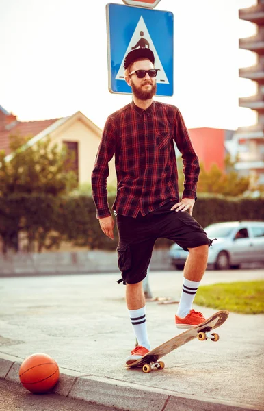 Young man in sunglasses with a skateboard on a street in the cit