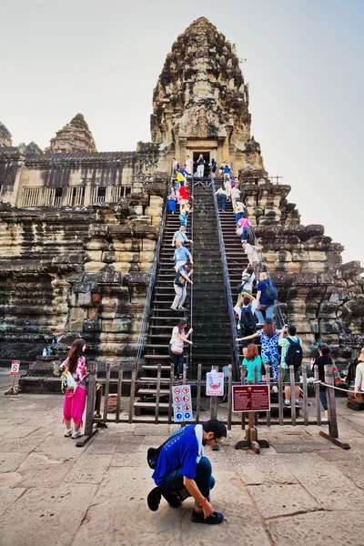 Tourists climb the steep steps to the highest temple of Angkor W