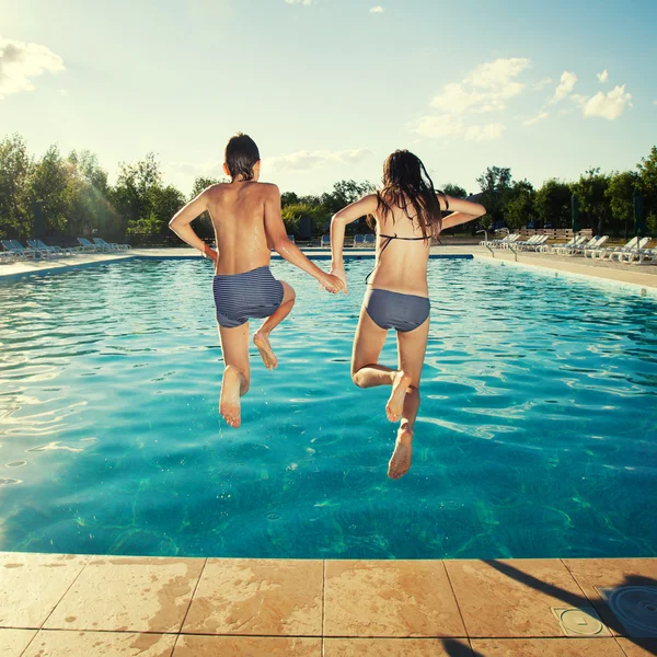 Couple jumping into pool. Summer vacations