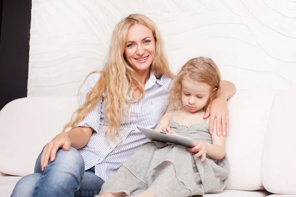 Mother and daughter wiht tablet at sofa