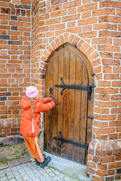 Little beautiful girl opens door in fortress