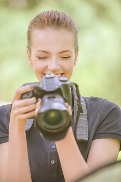 Smiling young woman photographs on camera