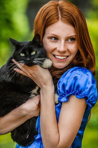 Red-haired smiling young woman with black cat