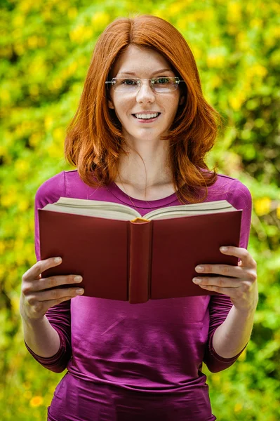 Red-haired young woman reads book
