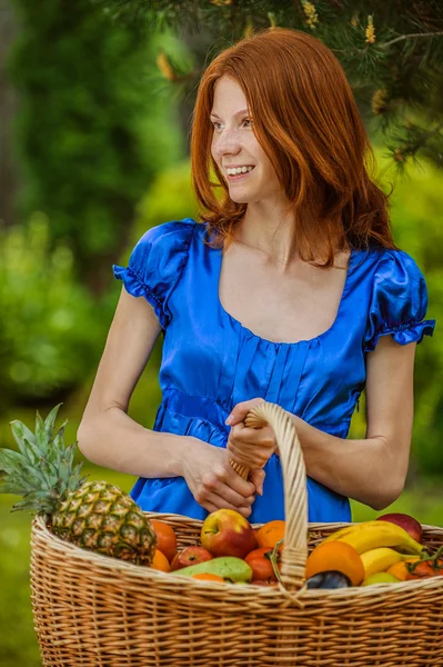 Red-haired smiling young woman with a fruit basket