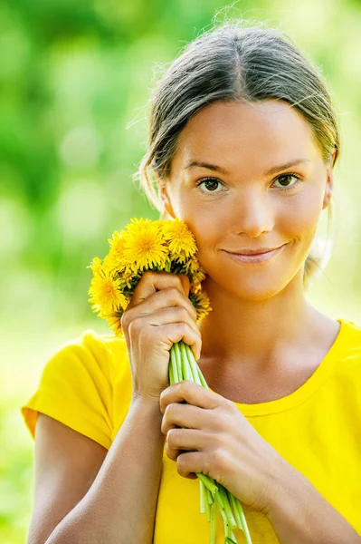 Young woman in with bouquet of dandelions
