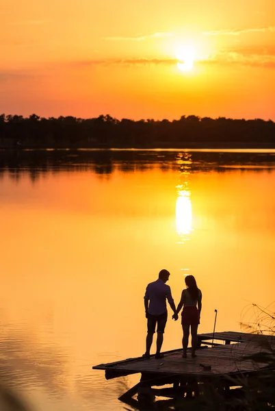 Couple in love back light silhouette at lake sunset