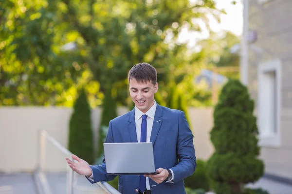 Successful businessman standing in the street holding a laptop