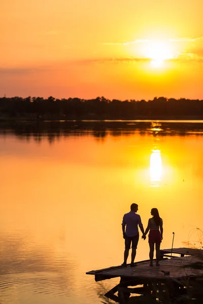 Couple in love back light silhouette at lake sunset
