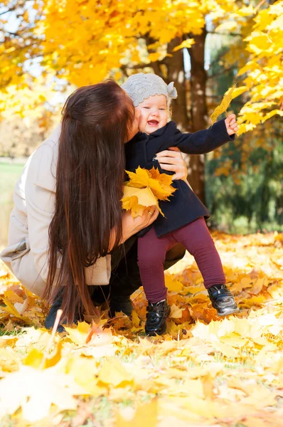 Young happy mother with daughter in autumn park