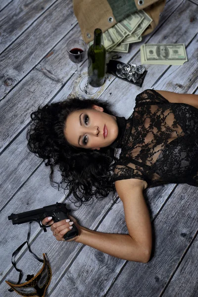 Young girl with a gun money and a bottle of wine