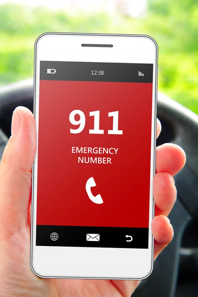 Hand holding mobile phone 911 emergency number in car