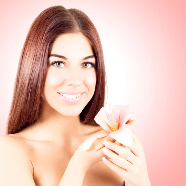Pretty nice woman with pink flower in hands on pink background. Smiling woman with white teeth.