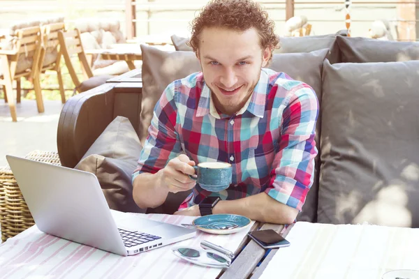 Happy hipster drinking coffee in the city cafe during lunch time with notebook. Modern lifestyle.