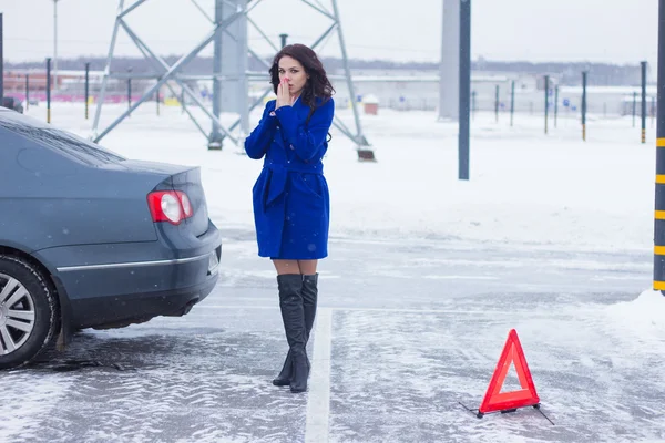 Frozen woman warms her hands on the street and waiting for a tow truck