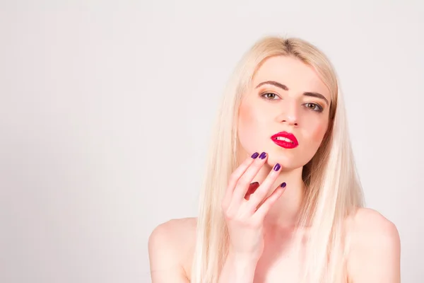 Blonde woman with red lips and with a manicure touching her face. Manicure.