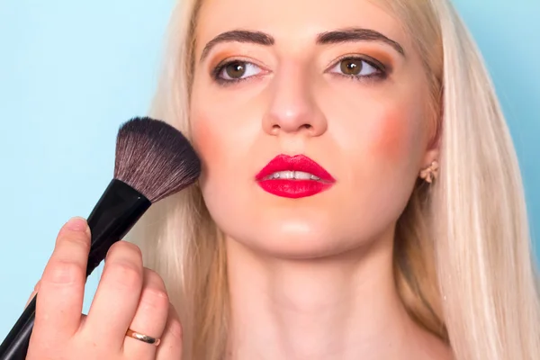 Makeup artist paints a woman blush cheekbones. Makeup.