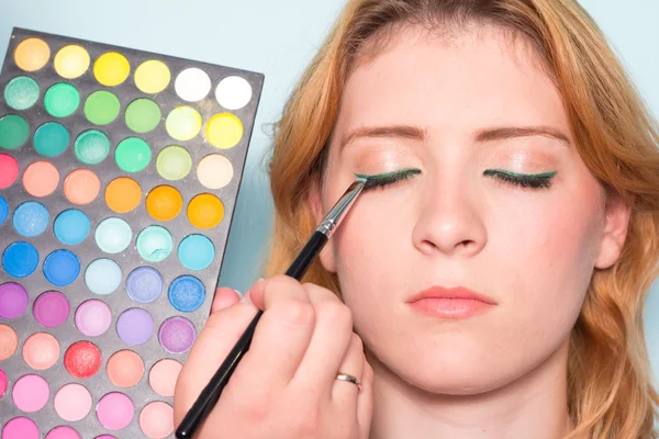 Makeup artist paints a eyes of woman. Makeup.