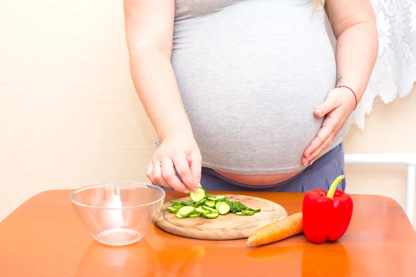 Pregnant woman eating cut cucumber. Diet for pregnant women.