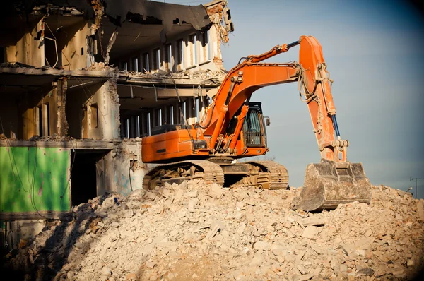 Orange big digger destroys building