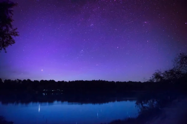 Night sky with many stars on lake