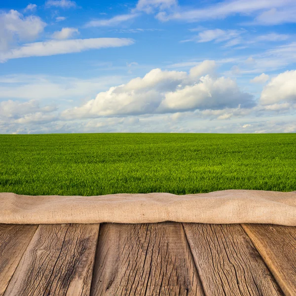 Wooden deck table over beautiful meadow with blue sky