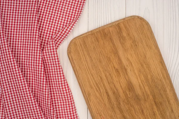 Empty kitchen cutting board. Wooden table covered with red check