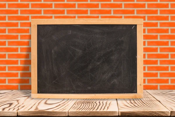 Blank blackboard on diagonal wooden table at red brick wall,Temp