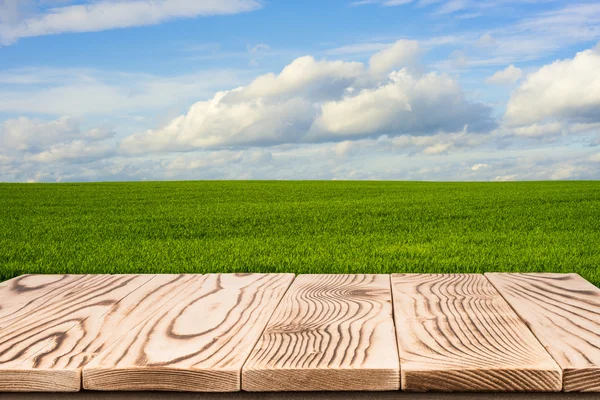 Wooden deck table over beautiful meadow with blue sky