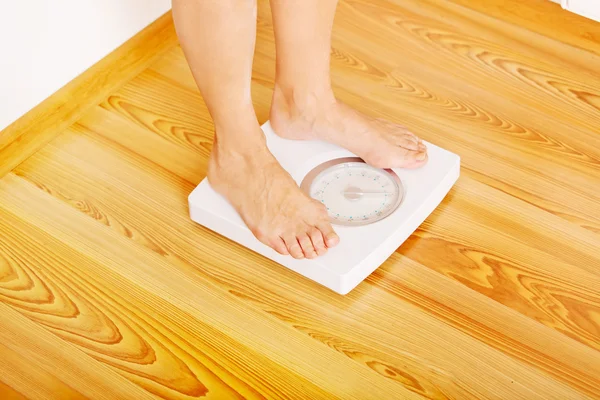 Senior woman standing on weight scale in living room